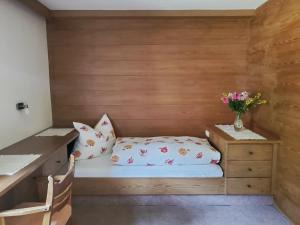 a small room with a bed and flowers in it at Haus an der Sonne FeWo 2 in Biberwier