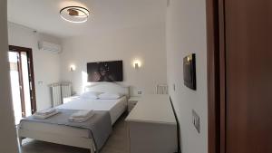a white bedroom with a bed and a tv on the wall at Villa Saponaro - Affittacamere in Torre Lapillo