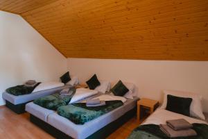 three beds in a room with a wooden ceiling at Jambrichova chata in Vysoké Tatry