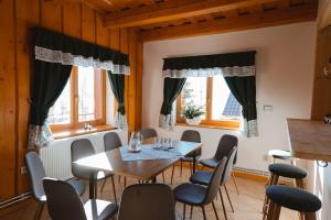 a dining room with a table and chairs and windows at Jambrichova chata in Vysoké Tatry