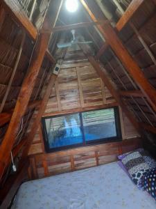 een kamer met een dak, een bed en een raam bij Tiliponan Nipa Hut in Buenavista