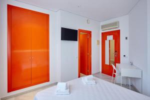 Habitación blanca con puertas naranjas y mesa blanca en Hotel DL Port, en Castellón de la Plana
