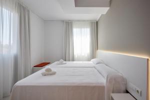 a white bedroom with two beds and a window at Hotel DL Port in Castellón de la Plana