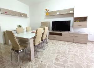 a dining room with a table and chairs and a television at Le Rose Apartment in Ortona