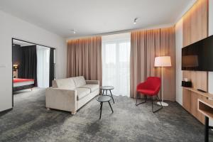 een woonkamer met een bank en een rode stoel bij Best Western Plus Hotel Rzeszow City Center in Rzeszów