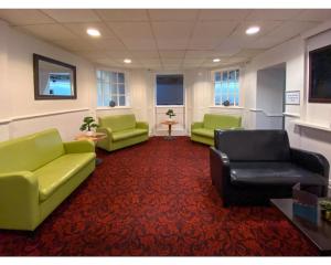 a waiting room with green couches and a red carpet at The Tor Park Hotel in Torquay