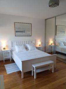 a white bedroom with a large white bed and mirrors at Apartment NINA in Rab