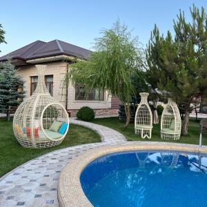 a swimming pool with two chairs next to a house at Zima-Leto in G‘azalkent