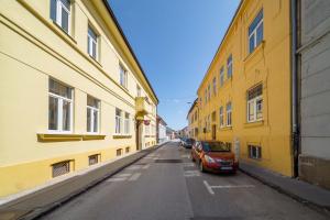 an alley with yellow buildings and a car parked on the street at GUDU apartments in Košice