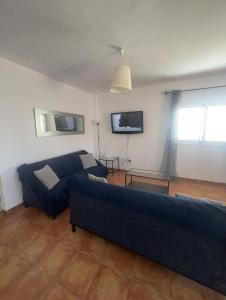 Una sala de estar con un sofá azul y un televisor. en Casita con piscina privada, en Igueste