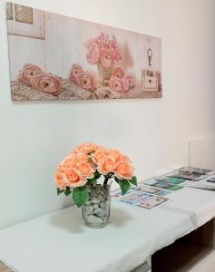 un vase rempli de roses oranges assis sur une table dans l'établissement Le Rose Apartment, à Ortona