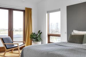 een slaapkamer met een bed, een stoel en ramen bij Eyvindarholt Guesthouse in Álftanes