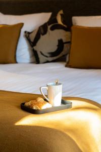 - un plateau avec une tasse de café et une viennoiserie sur un lit dans l'établissement Les Villas du Château de Lastours, à Portel-des-Corbières