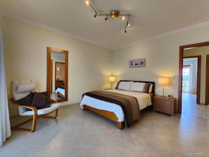 a bedroom with a bed and a chair and a mirror at Vila Limoeiro in Salir de Porto
