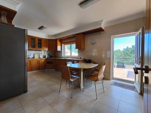 a kitchen with a table and chairs and a large window at Vila Limoeiro in Salir de Porto