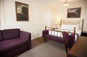 a bedroom with a bed and a couch and a chair at Cock Hotel by Greene King Inns in Stony Stratford