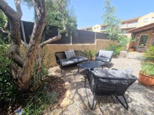 eine Terrasse mit Stühlen, einem Tisch und einem Baum in der Unterkunft Bel appartement avec jardin in Aix-en-Provence