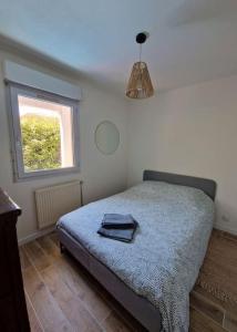 ein Schlafzimmer mit einem Bett mit einer blauen Decke und einem Fenster in der Unterkunft Bel appartement avec jardin in Aix-en-Provence