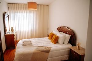 1 dormitorio con 1 cama con sábanas blancas y almohadas de color naranja en Apartamento T3 Vista Mar - Anzol en Vila do Conde
