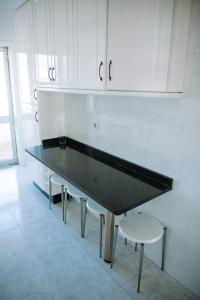 una encimera negra en una cocina con armarios blancos en Apartamento T3 Vista Mar - Anzol en Vila do Conde
