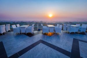 einen Balkon mit Tischen und Stühlen bei Sonnenuntergang in der Unterkunft Havana Hotel Mandalay in Mandalay
