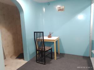 une table et une chaise dans une pièce dotée d'un mur bleu dans l'établissement Flying House Hostel, à Arequipa