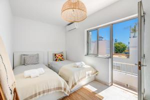 deux lits dans une chambre avec fenêtre dans l'établissement Casa dos Amigos, à Alvor