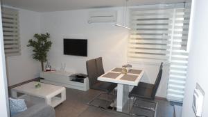uma sala de estar com uma mesa e cadeiras e uma televisão em Mandy Apartman em Baska