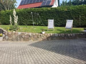 dos sillas sentadas en el césped cerca de una pared de piedra en Heublein, en Poseritz