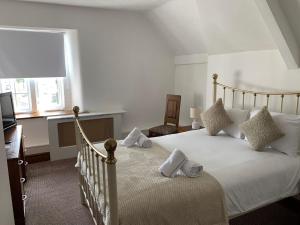 a bedroom with a bed with white sheets and a window at The Bull Hotel in Llangefni