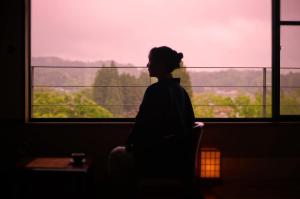 a woman sitting in front of a window looking out at Itsukushien 