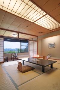 a room with a table and chairs and a large window at Itsukushien 