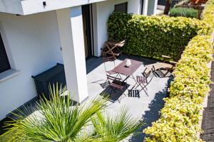 a patio with a table and chairs and a hedge at Appartement de caractère avec Jacuzzi in Fréjus