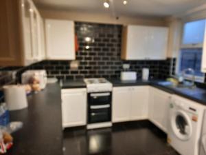a kitchen with white cabinets and a black counter top at Home away from home with fantastic spacious rooms in Abbey Wood