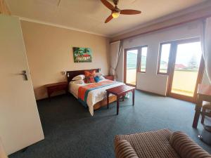 a bedroom with a bed and a ceiling fan at First Group Perna Perna Mossel Bay in Mossel Bay