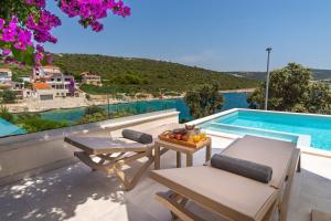 un patio con tavolo e sedie e una piscina di Beachfront Villa Larisa with Whirlpool, Media room a Rogoznica (Rogosnizza)