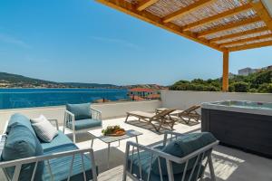 un patio con sedie, divano e tavolo di Beachfront Villa Larisa with Whirlpool, Media room a Rogoznica (Rogosnizza)