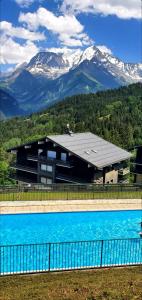 un bâtiment avec une piscine en face d'une montagne dans l'établissement Appartement Saint Gervais les Bains piscine et vue imprenable Mont Blanc, à Saint-Gervais-les-Bains