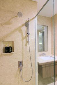 uma casa de banho com um chuveiro e um lavatório. em Calma 31 Apartment em Makassar