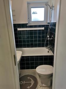 a bathroom with a toilet and a tub and a window at Haus Berlin 58 in Großenbrode