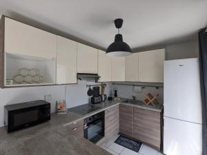 La cuisine est équipée de placards blancs et d'un four micro-ondes noir. dans l'établissement La Terrasse du tramway, Parking, 30min de Paris, à Bezons 4 autres photos