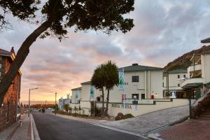 an empty street with buildings and a palm tree at First Group Perna Perna Mossel Bay in Mossel Bay