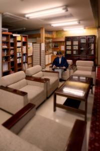 a man sitting in a library with tables and couches at Itsukushien 