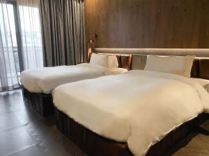 two beds in a hotel room with white sheets at CHECK inn Phnom Penh BKK1 in Phnom Penh