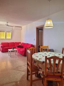 een woonkamer met een tafel en een rode bank bij Apartamento con vistas al mar in Villajoyosa