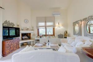 a living room with a white couch and a tv at Amelia Villa, Anthology Villas in Sani, ex Sani Luxury Villas Collection in Sani Beach