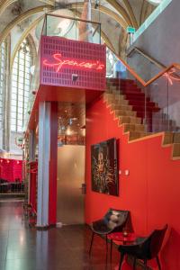 Kruisherenhotel Maastricht - Oostwegel Collection, member of Design Hotels في ماستريخت: درج في مبنى بجدار احمر