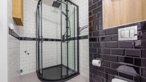 a glass shower in a bathroom with black and white tiles at Wiatrakowo, Sun & Snow in Tupadły