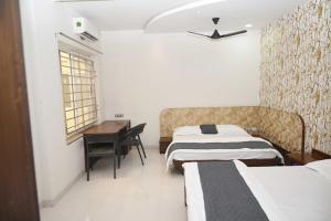 ein Hotelzimmer mit 2 Betten und einem Schreibtisch in der Unterkunft Shree haveli homestay in Ujjain