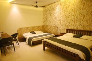 1 Schlafzimmer mit 2 Betten, einem Tisch und einem Schreibtisch in der Unterkunft Shree haveli homestay in Ujjain